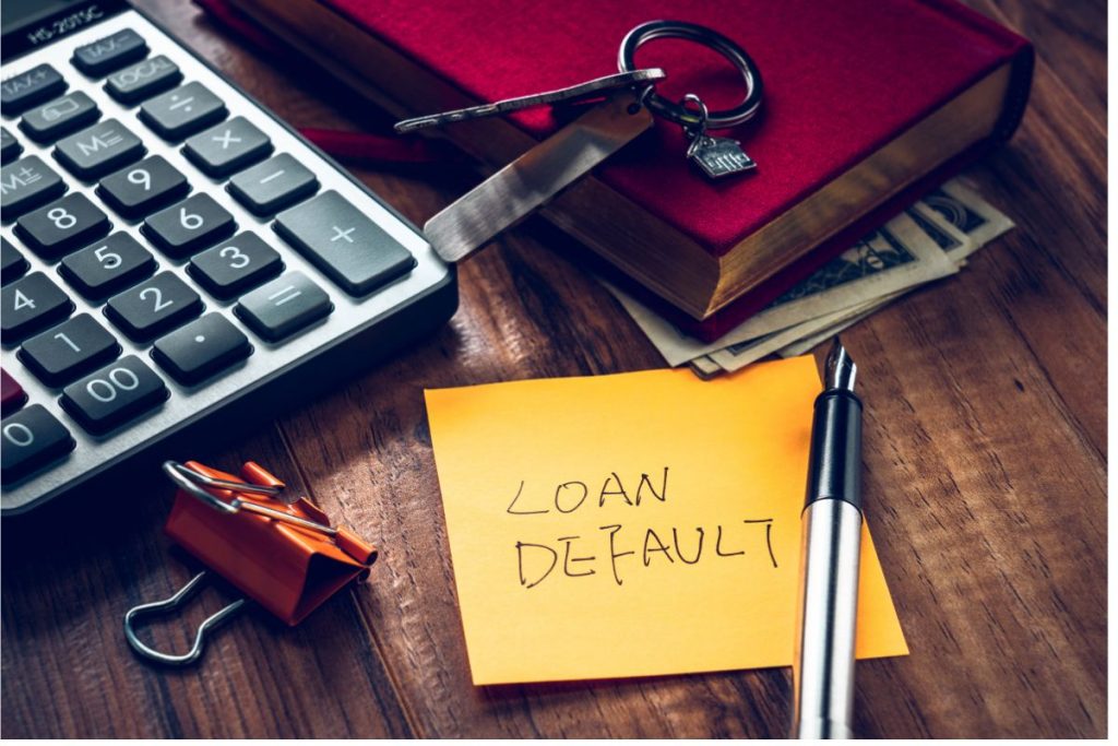 A calculator next to a sticky note reading loan default, evoking the concept of MCA debt relief