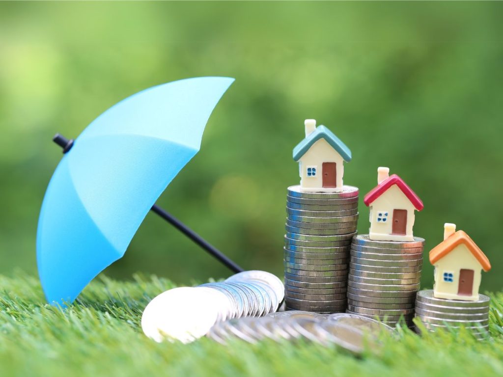 tiny plastic houses standing atop columns of coins, symbolizing that personal guarantees sometimes mean the bank can seize your home